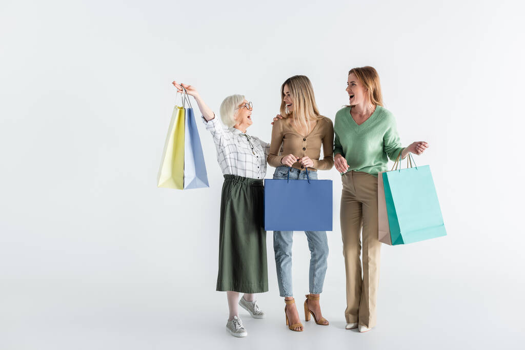 pełna długość trzech pokoleń radosnych kobiet trzymających torby na zakupy na białym - Zdjęcie, obraz