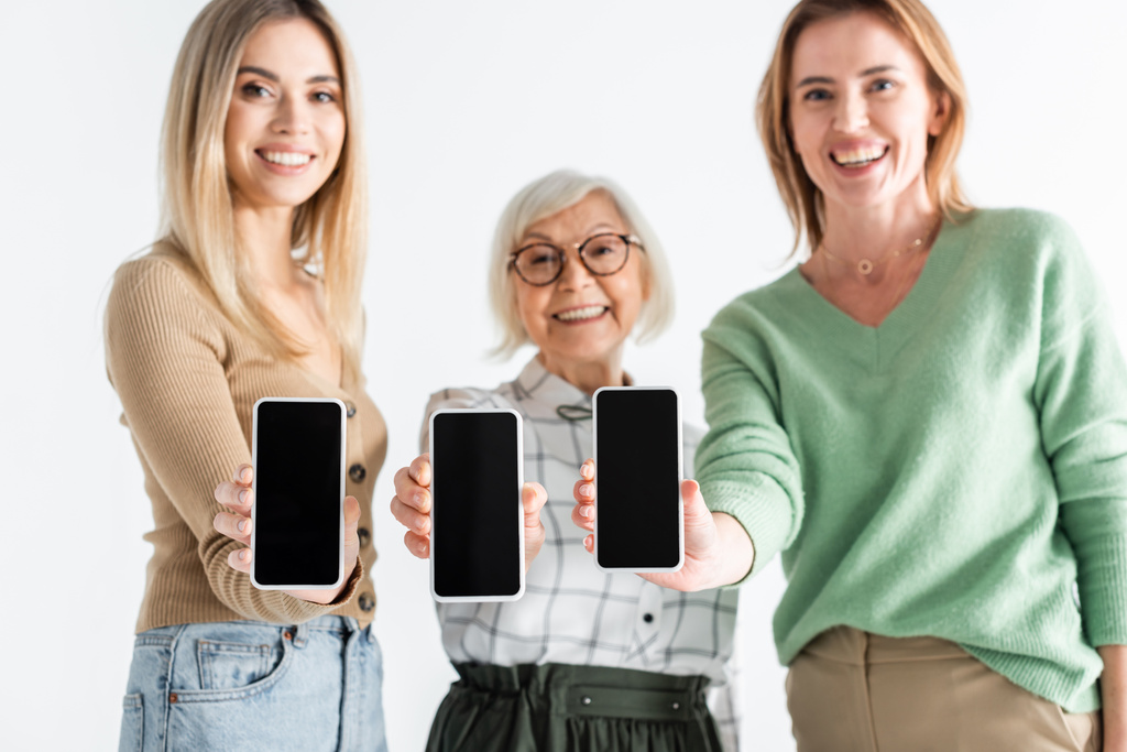kolme sukupolvea onnellisia naisia tilalla älypuhelimet tyhjä näyttö eristetty valkoinen - Valokuva, kuva