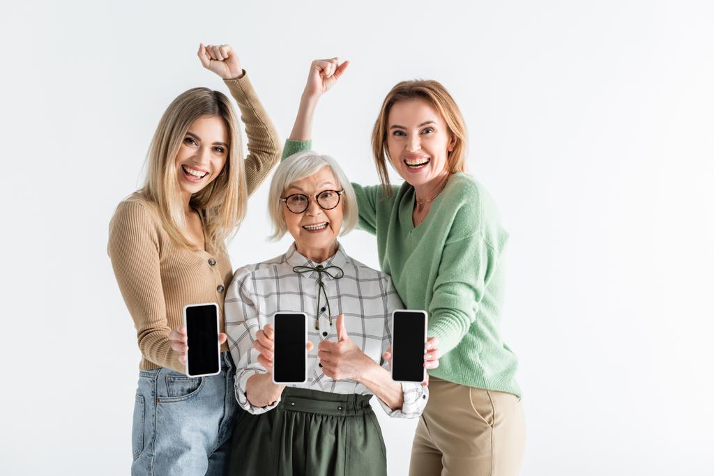 trois générations de femmes excitées tenant des smartphones avec écran blanc isolé sur blanc - Photo, image