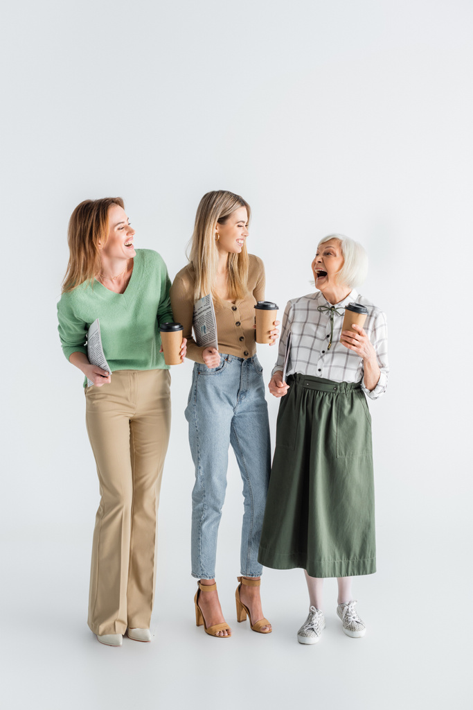 teljes hossza három generációs mosolygós nők kezében újságok és papírpoharak fehér - Fotó, kép