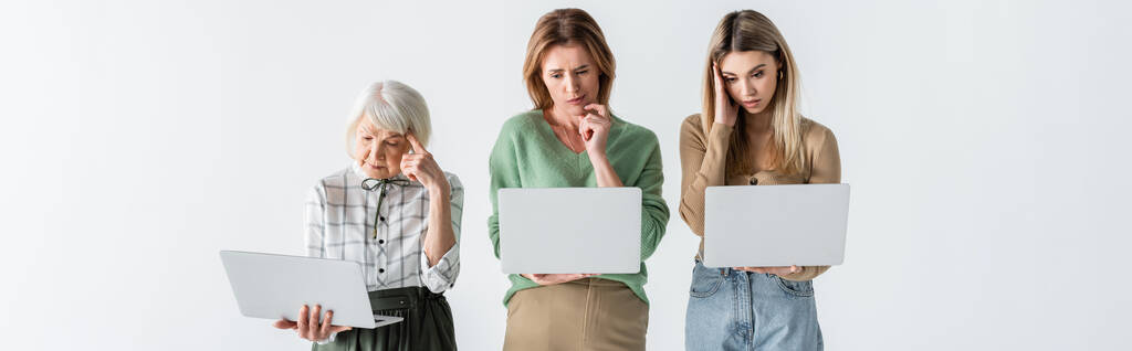 three generation of pensive women using laptops isolated on white, banner - Photo, Image