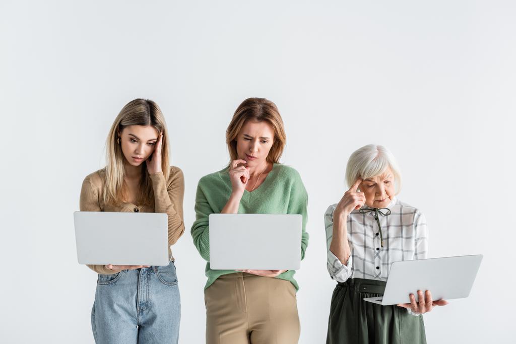 three generation of pensive women using laptops isolated on white - Photo, Image