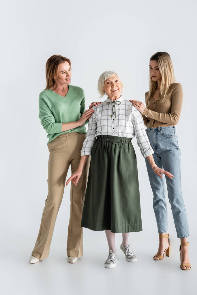 πλήρες μήκος των γυναικών κοιτάζοντας χαρούμενα ηλικιωμένη γυναίκα στα λευκά - Φωτογραφία, εικόνα
