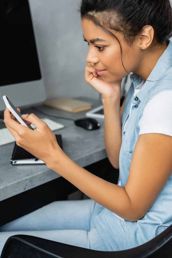 アフリカ系アメリカ人の若者が自宅でスマートフォンでメッセージを発信する様子を - 写真・画像