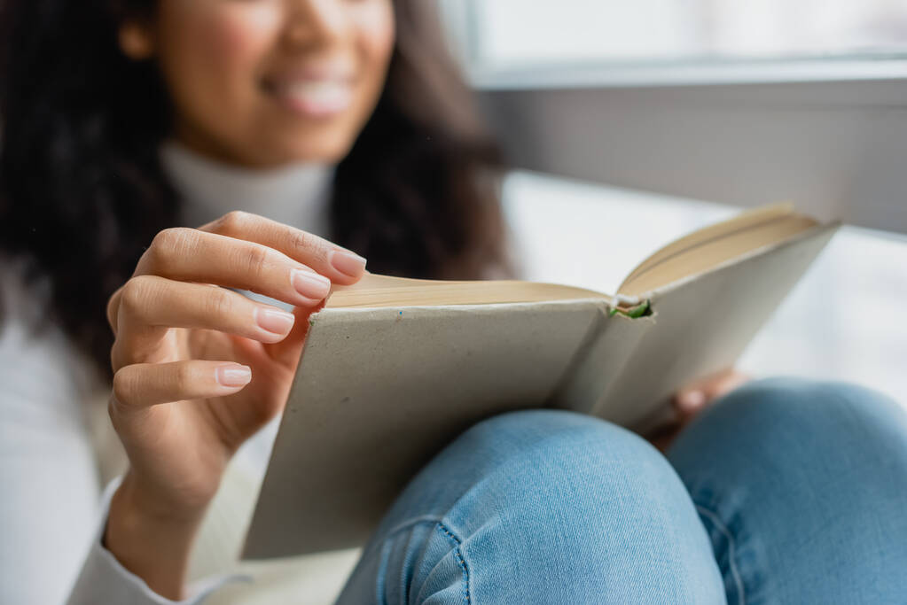 vista recortada de la mujer afroamericana leyendo libro en casa, fondo borroso - Foto, imagen