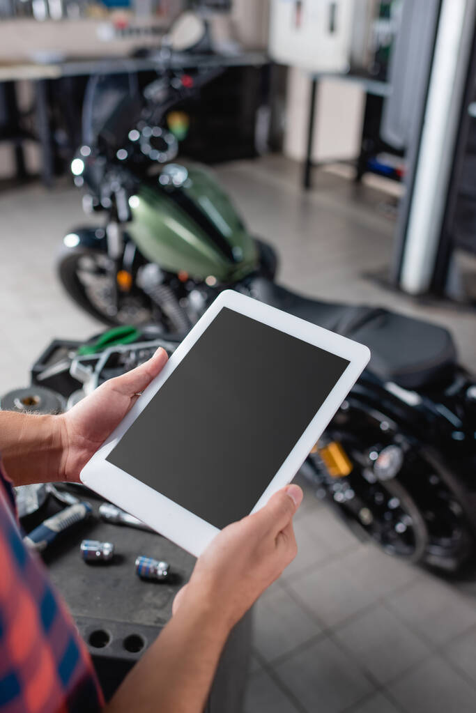 cropped view of repairman holding digital tablet with blank screen near motorcycle on blurred background - Photo, Image