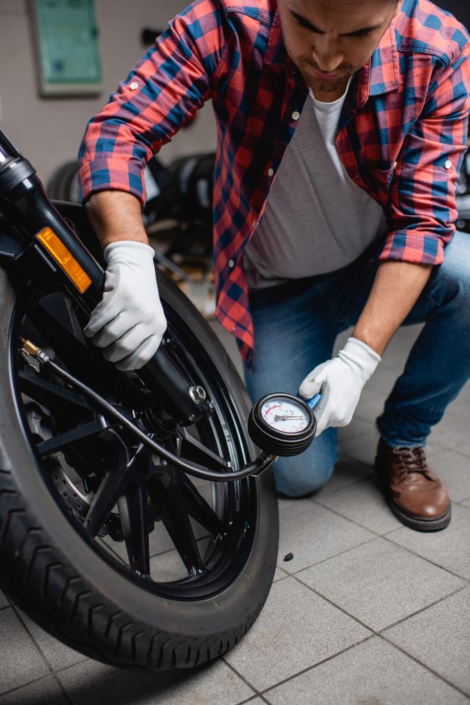 repairman measuring pressure in tire of motorcycle with air gauge - Photo, Image