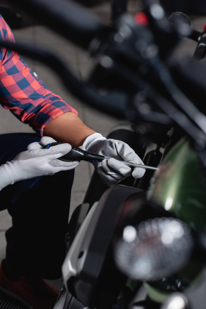 Motosiklet kontrolü sırasında tornavida kullanan tamirci görüntüsü, bulanık önplan - Fotoğraf, Görsel