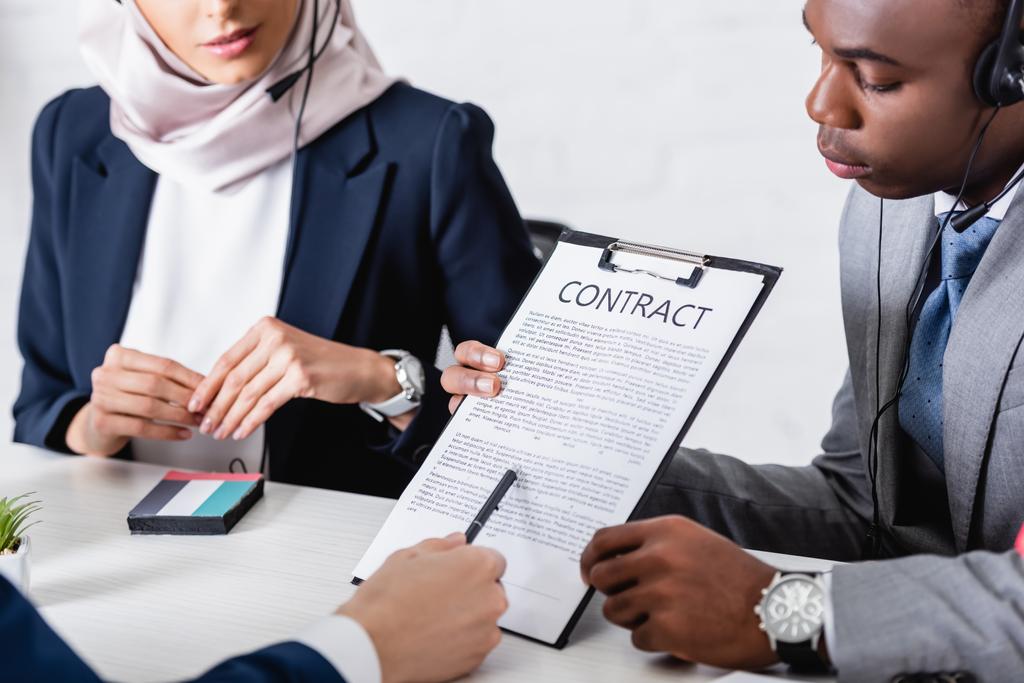 cropped view of interpreter pointing with pen at contract near african american and arabian business partners - Photo, Image