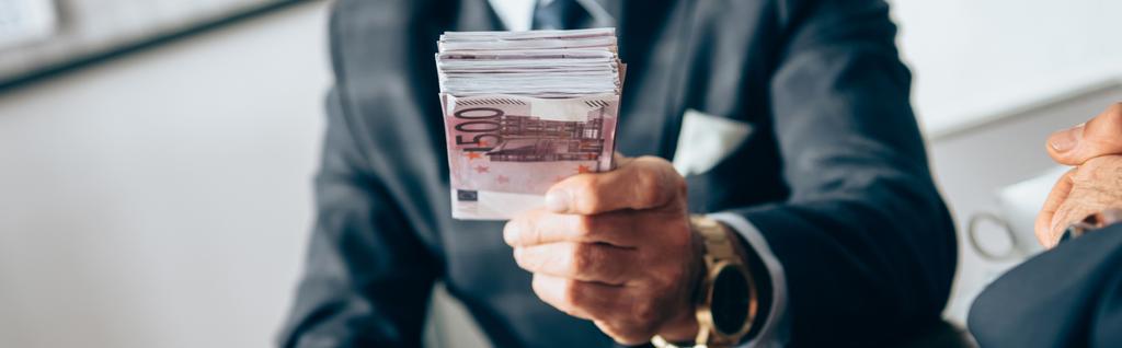 Обрізаний вид інвестора, який тримає євро банкноти біля бізнесмена на розмитому фоні, банер
  - Фото, зображення