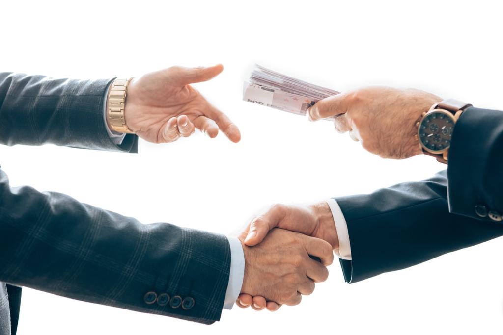 Ausgeschnittene Ansicht von Geschäftsleuten, die Geld in der Hand halten und weiße Hände schütteln  - Foto, Bild