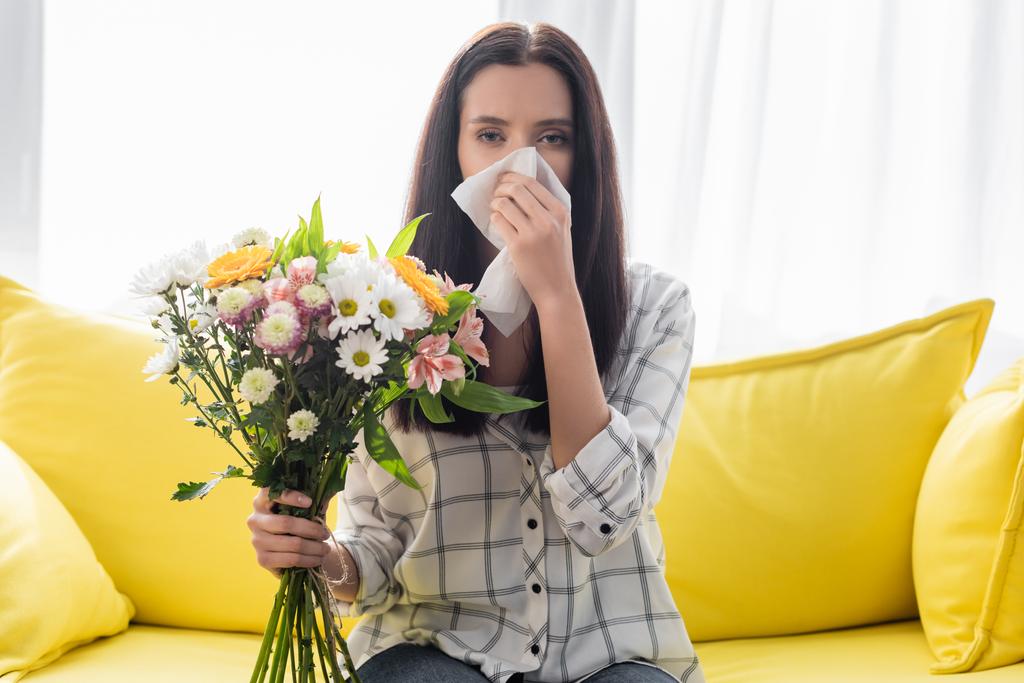 jeune femme tenant des fleurs et souffrant d'allergie à la maison - Photo, image