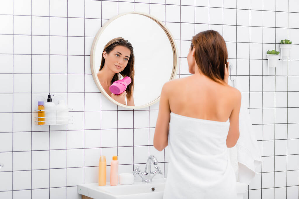 白いテリータオルに包まれた若い女性バスルームの鏡の近くで髪を乾かし - 写真・画像