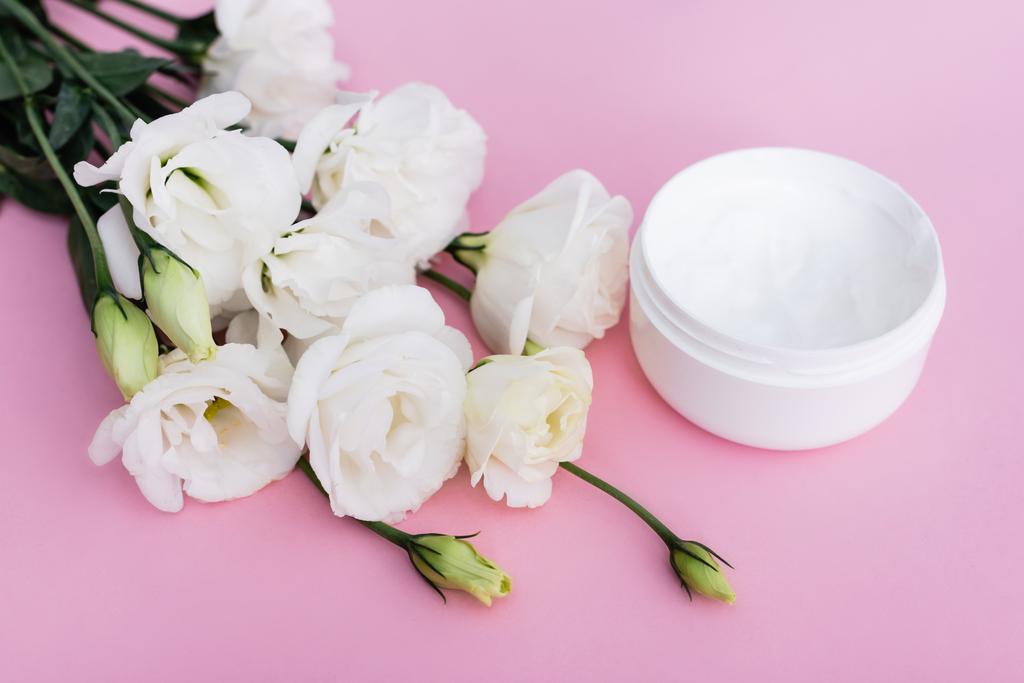 білі квіти еустоми та косметичний крем на рожевому фоні
 - Фото, зображення