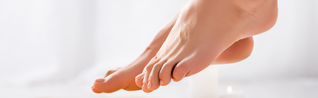 pies femeninos arreglados con esmalte de uñas brillante en las uñas de los pies sobre fondo blanco, pancarta - Foto, imagen