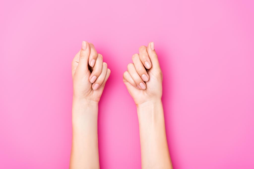 vrchní pohled na ženské ruce s pastelovým lakem na nehty na růžovém pozadí - Fotografie, Obrázek
