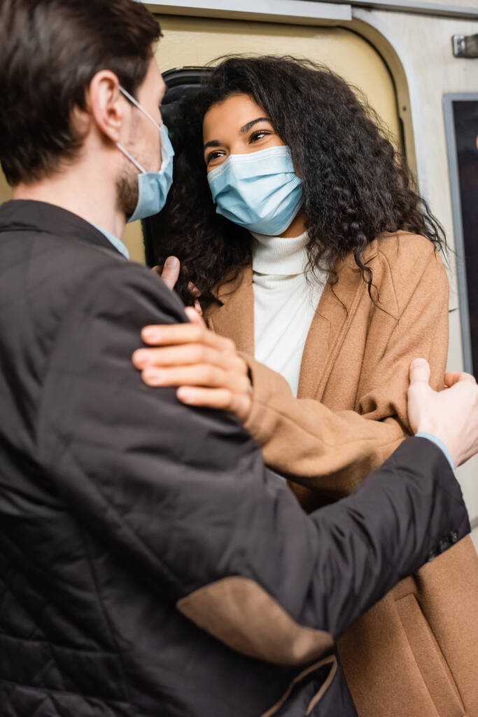 Африканська американка в медичній масці обіймає хлопця в метро. - Фото, зображення