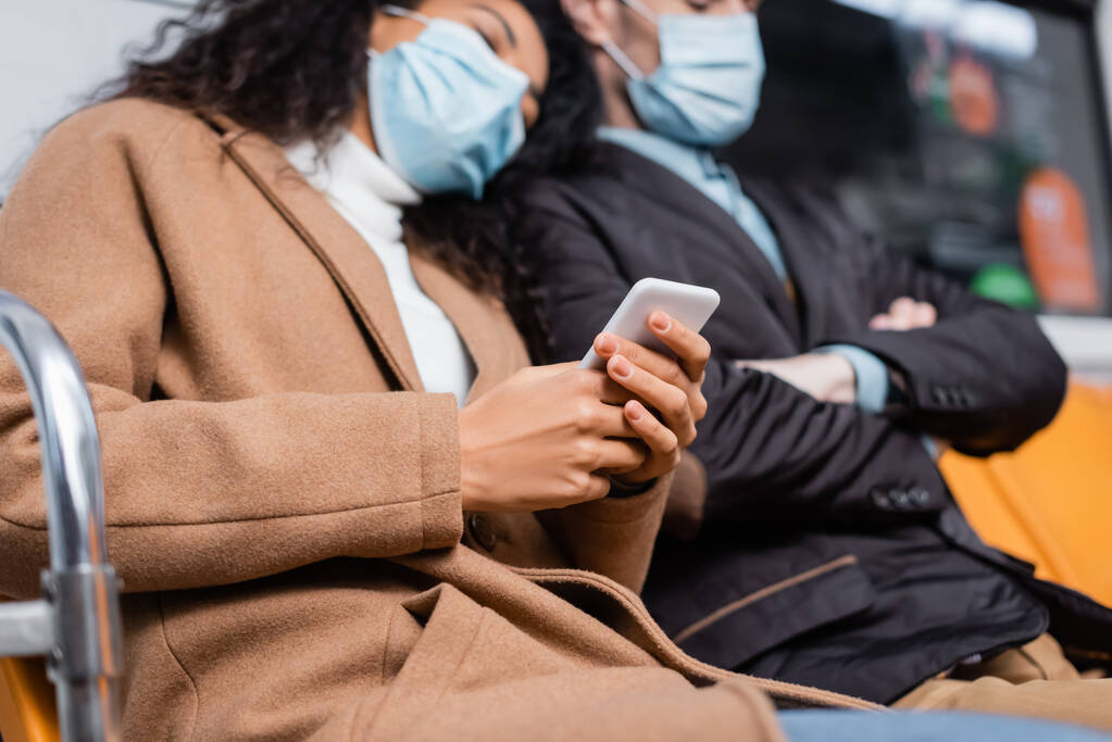 african american woman in medical mask holding smartphone and leaning on man in subway  - Photo, Image