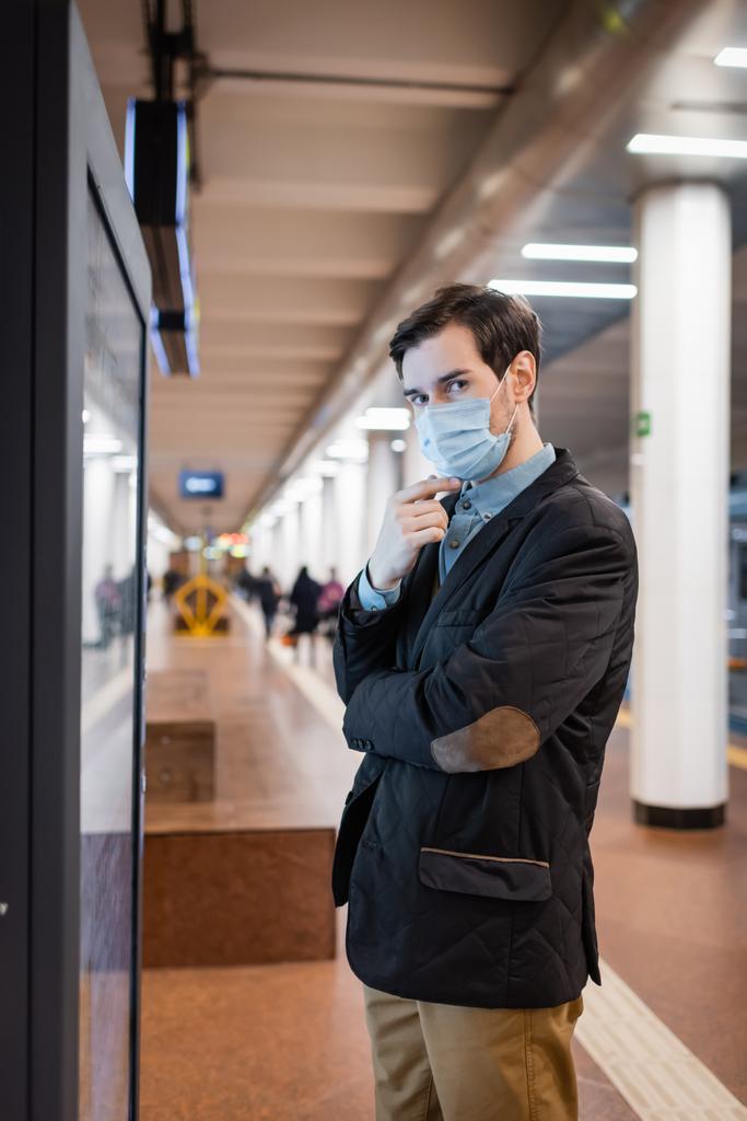 mężczyzna w medycznym człowiek patrząc na kamery na peronie w metrze  - Zdjęcie, obraz