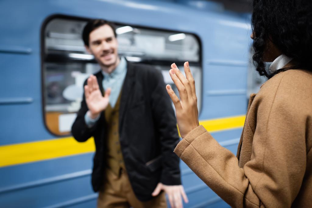 Afričanky americká žena a muž mává rukama v blízkosti vozu v metru na rozmazaném pozadí  - Fotografie, Obrázek