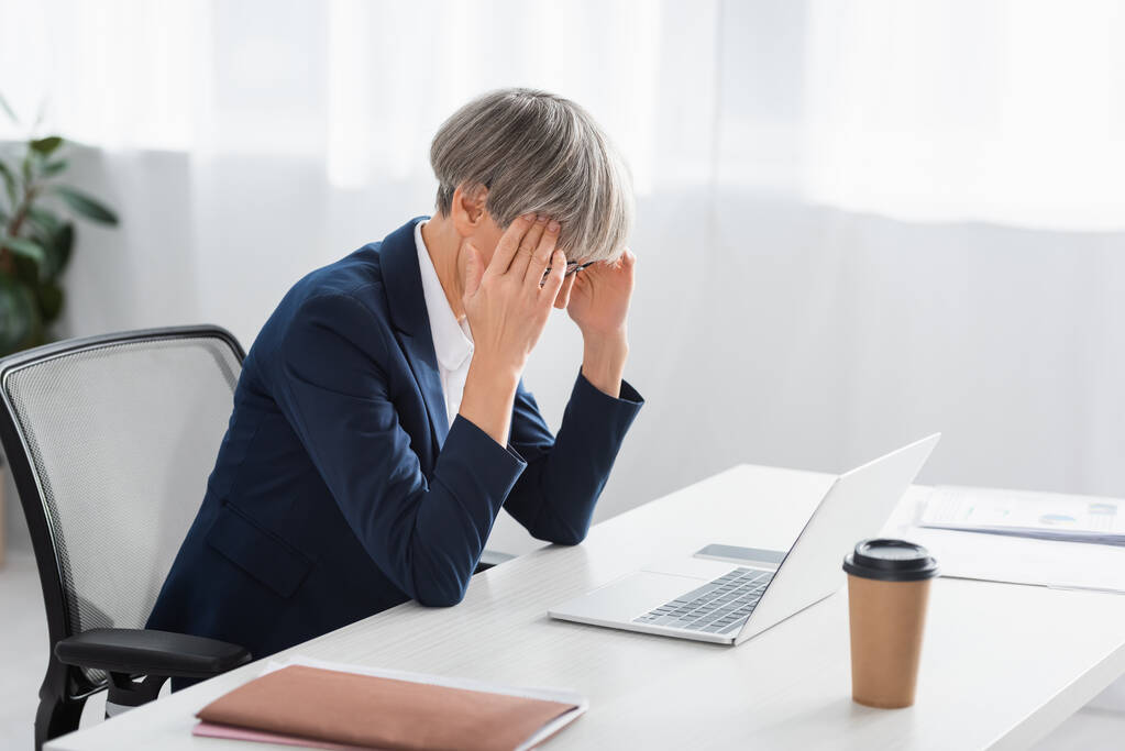 esausta e di mezza età donna d'affari che soffre di mal di testa in ufficio - Foto, immagini