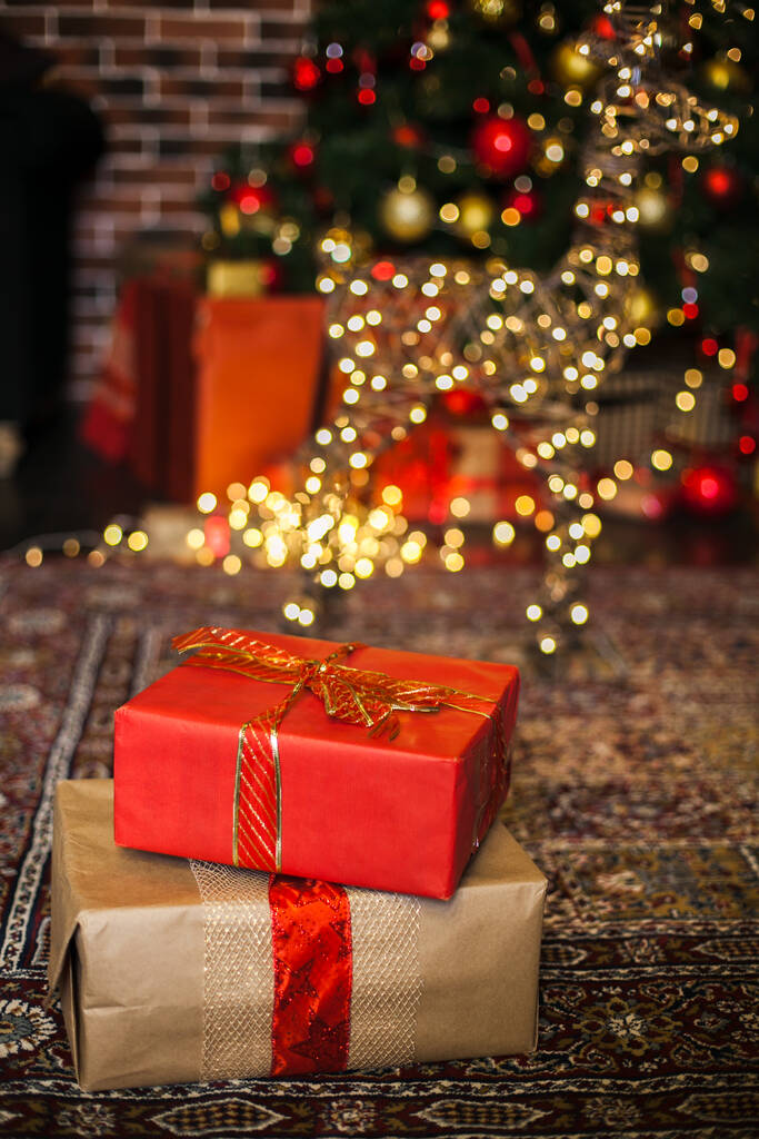 Weihnachtsgeschenke in braunem und rotem Papier auf dem Dachboden eingewickelt, Hintergrund mit Weihnachtslichtern Bokeh der verschwommenen Weihnachtsbaum. Kopierraum - Foto, Bild