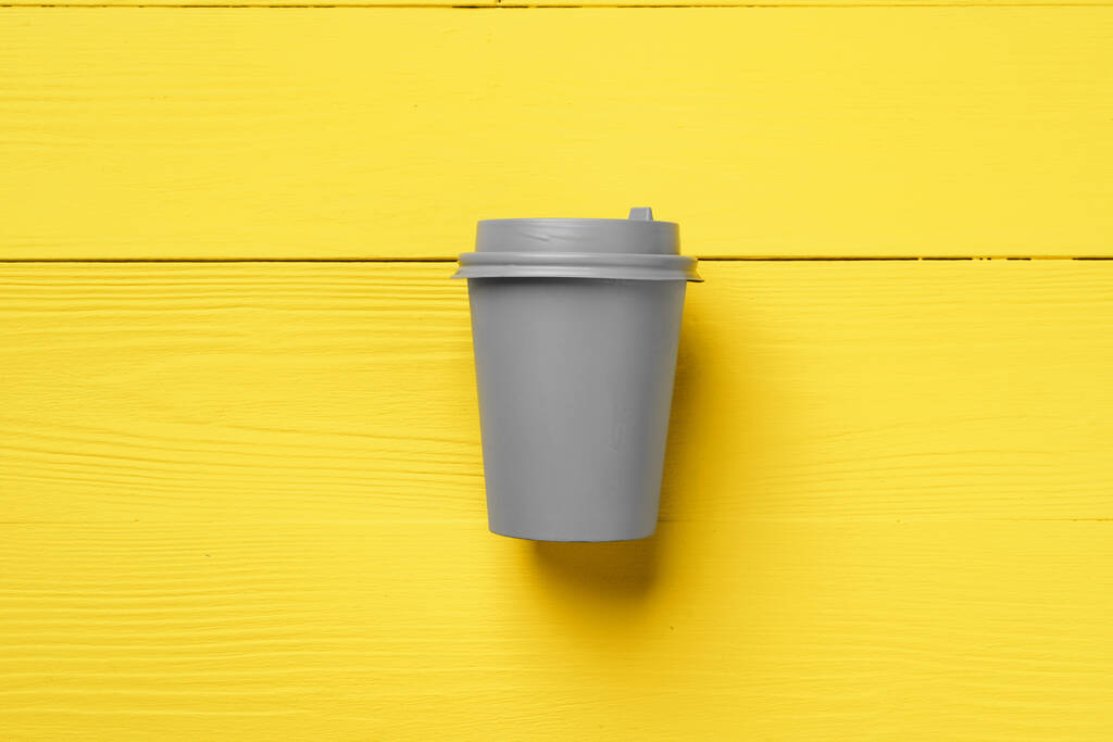 Kertakäyttöinen kahvikuppi keltaisilla harmailla väreillä - Valokuva, kuva