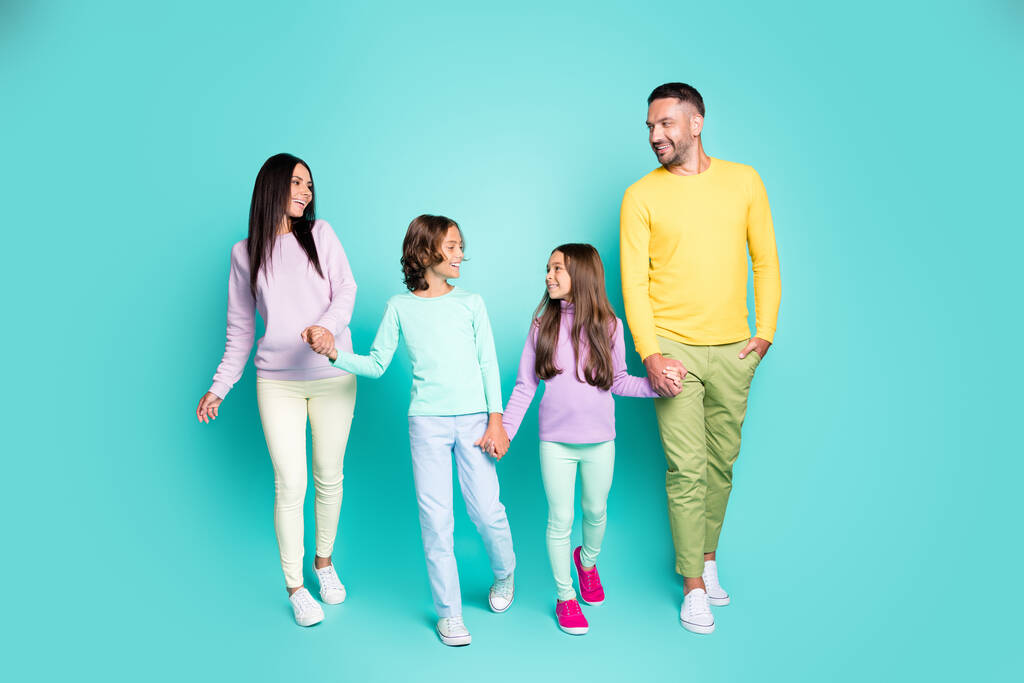 Kuva muotokuva suuresta perheestä, jossa pienet lapset menevät kävelylle pitäen kädestä kiinni elävällä turkoosin värillisellä taustalla - Valokuva, kuva