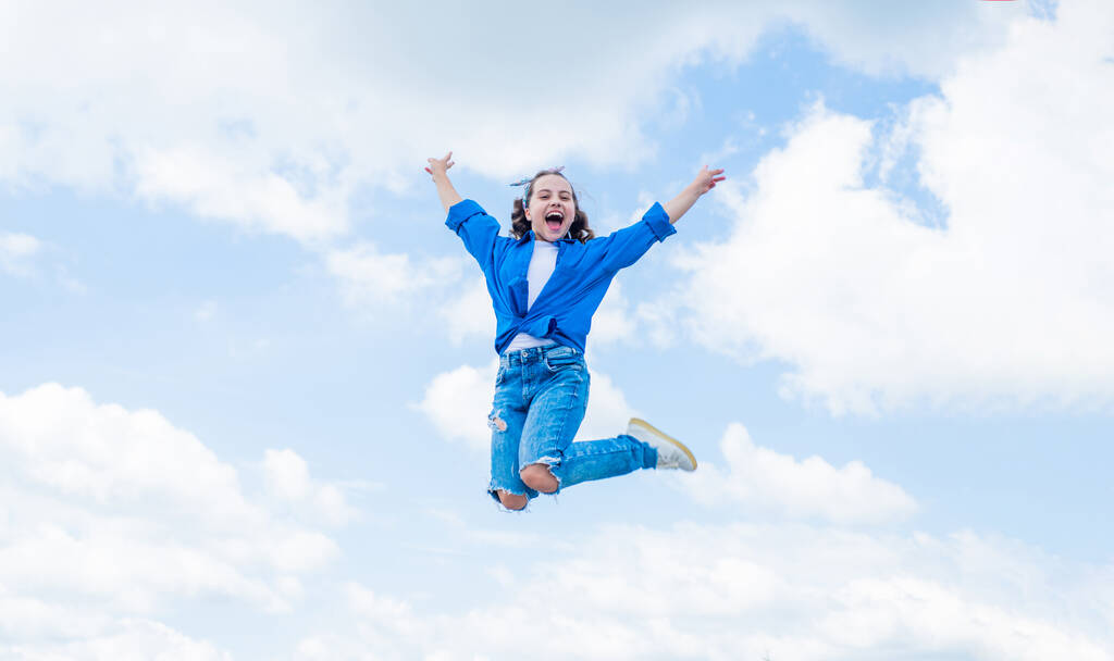 fröhliches Kind springen in lässiger Jeansbekleidung im Freien, Glück - Foto, Bild