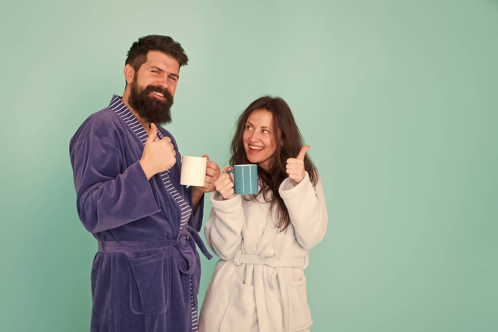 Vacation starting here. Man and woman happy together. Family traditions. Couple in cozy bathrobes enjoy lazy weekend. Drinking coffee. Spa and relax. Hotel breakfast service. Coffee is our tradition - Photo, Image
