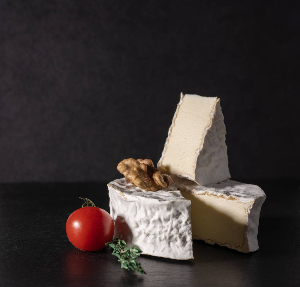 Siyah arka planda domates ve cevizli nefis brie peyniri. Brie peyniri. Camembert peyniri. Taze Brie peyniri ve taş tahtada bir dilim. İtalyan, Fransız peyniri. kare resim - Fotoğraf, Görsel