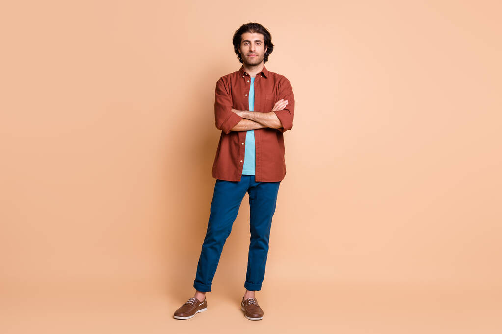 Full length φωτογραφία του νέου άνδρα διπλωμένα χέρια αυτοπεποίθηση πρόσωπο φορούν καφέ t-shirt μπλε παντελόνι παπούτσια απομονωμένο μπεζ χρώμα φόντο - Φωτογραφία, εικόνα