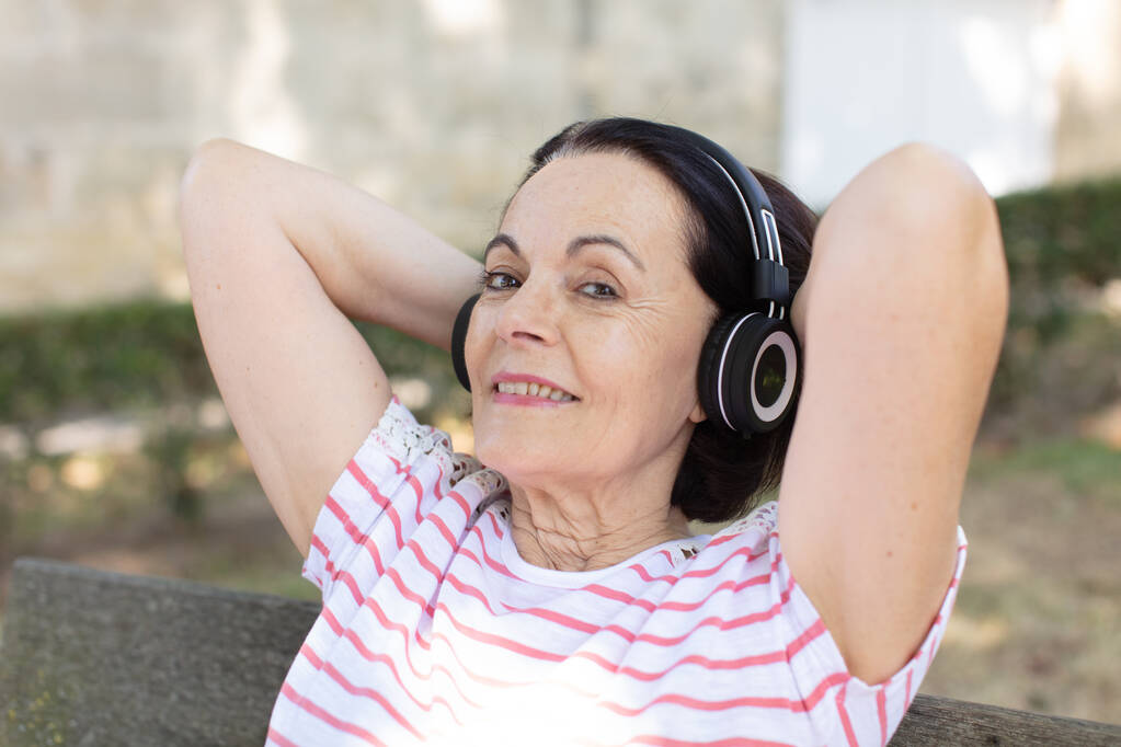 felice donna anziana ascoltando gli heaphones - Foto, immagini