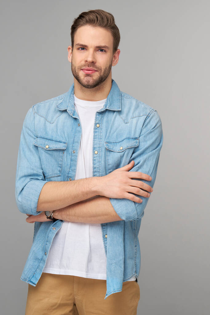 Πορτρέτο του νεαρού όμορφου καυκάσιου άνδρα με τζιν πουκάμισο σε ανοιχτό φόντο - Φωτογραφία, εικόνα