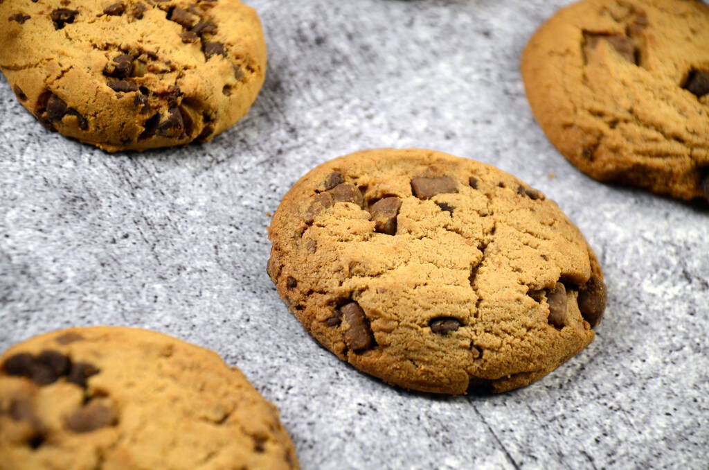 Een close-up van vers gebakken heerlijke chocolade chip koekjes op een grijs oppervlak - Foto, afbeelding