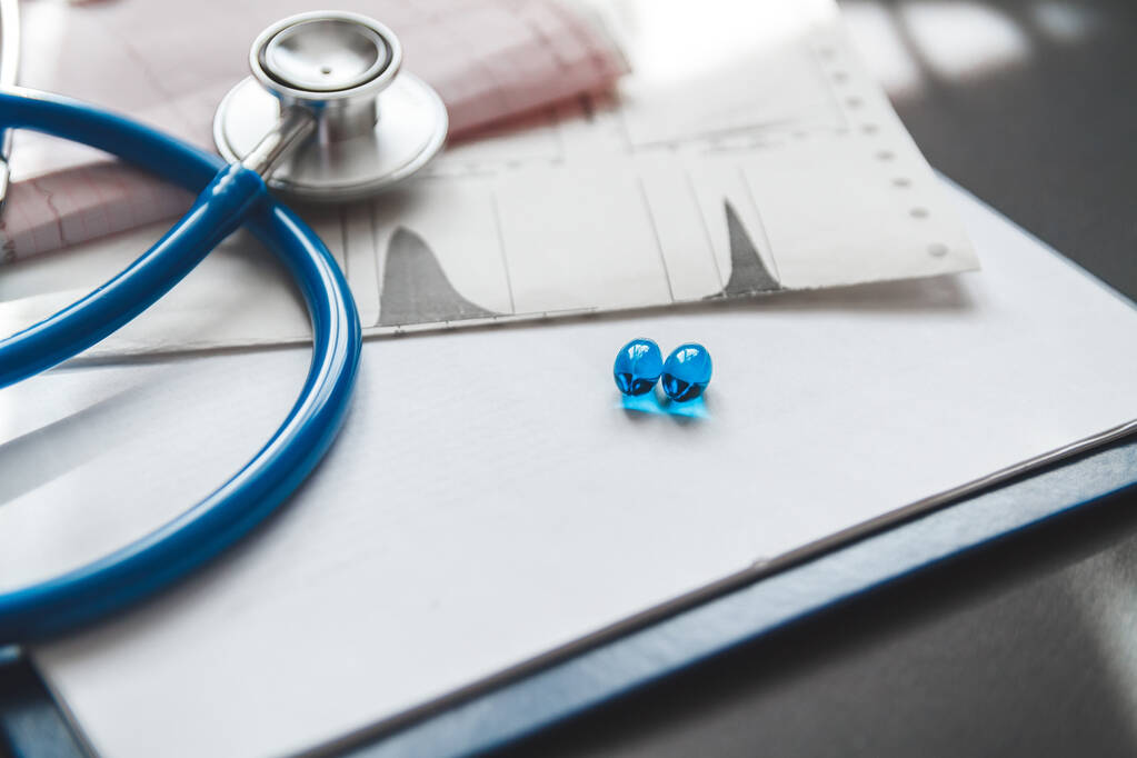 Medische kaart van een patiënt close-up, stethoscoop en pillen op het bureau van de dokter - Foto, afbeelding