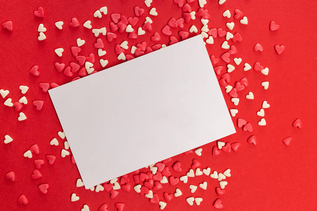 Пустая карточка и маленькие сердечные брызги на красном фоне - Фото, изображение