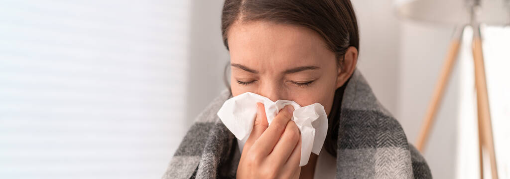 Une femme malade se sent mal de rester à la maison. Jeune fille avec des symptômes de grippe toussant dans les tissus couvrant le nez lors des éternuements comme COVID 19 prévention. Cultures panoramiques - Photo, image