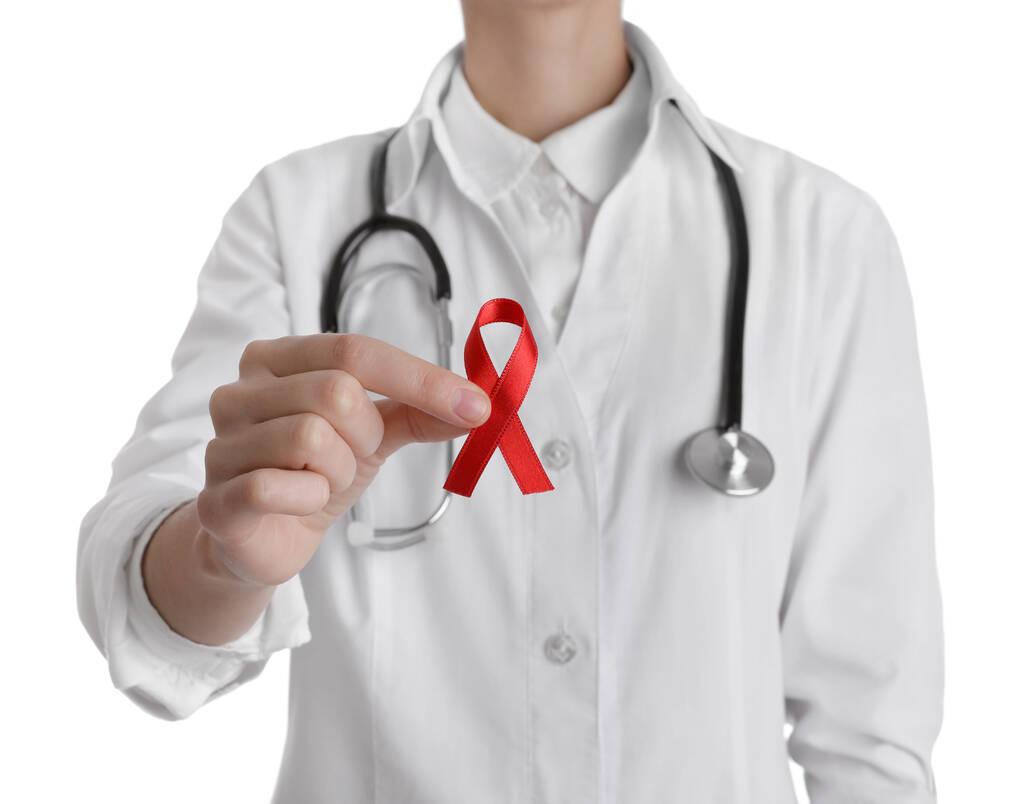 Doctor holding red ribbon on white background, closeup. AIDS awareness month - Photo, Image