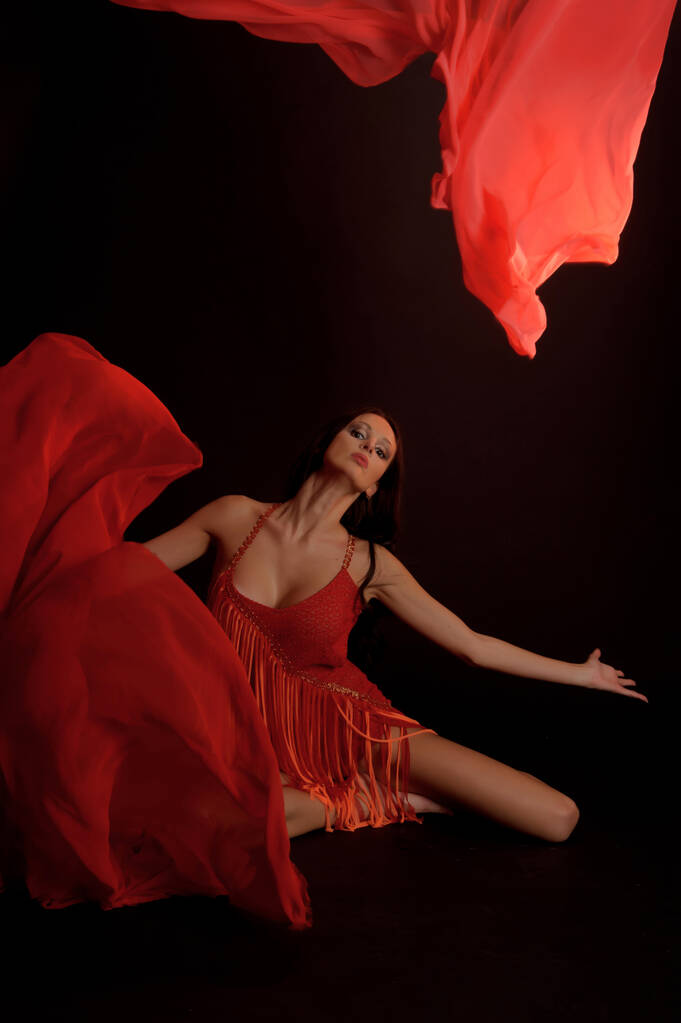 σέξι μελαχρινή με κόκκινο κοστούμι σε σκούρο φόντο στο στούντιο - Φωτογραφία, εικόνα