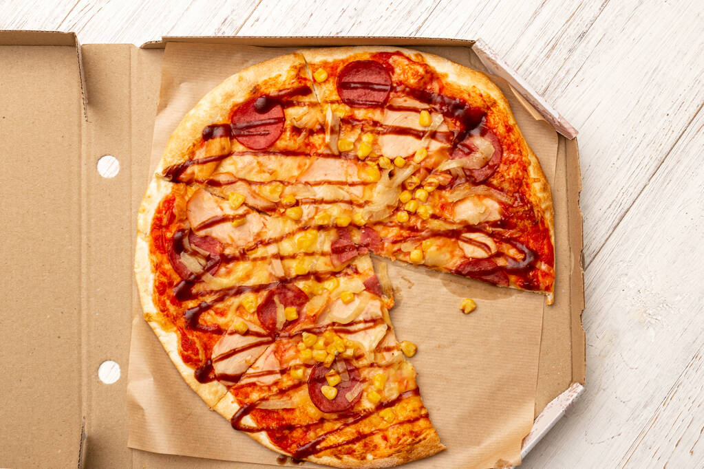 Pizza in einem Karton auf weißem Holzgrund. - Foto, Bild