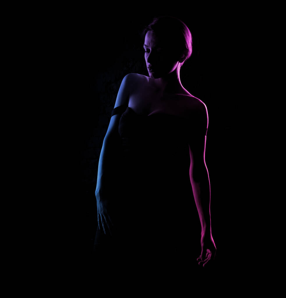 Σιλουέτα ενός όμορφου γυναικείου σώματος σε σκούρο φόντο. Μπλε και ροζ φως. - Φωτογραφία, εικόνα