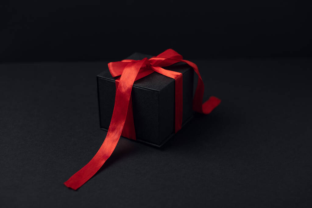 Κουτιά δώρου μαύρα με κόκκινη κορδέλα σε μαύρο φόντο με χώρο αντιγραφής για κείμενο. Η έννοια της ημέρας του Αγίου Βαλεντίνου. - Φωτογραφία, εικόνα