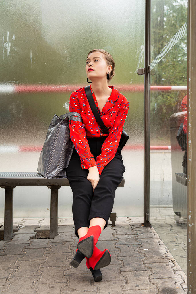 Modèle fille blonde est assis sur l'arrêt de bus à l'extérieur - Photo, image