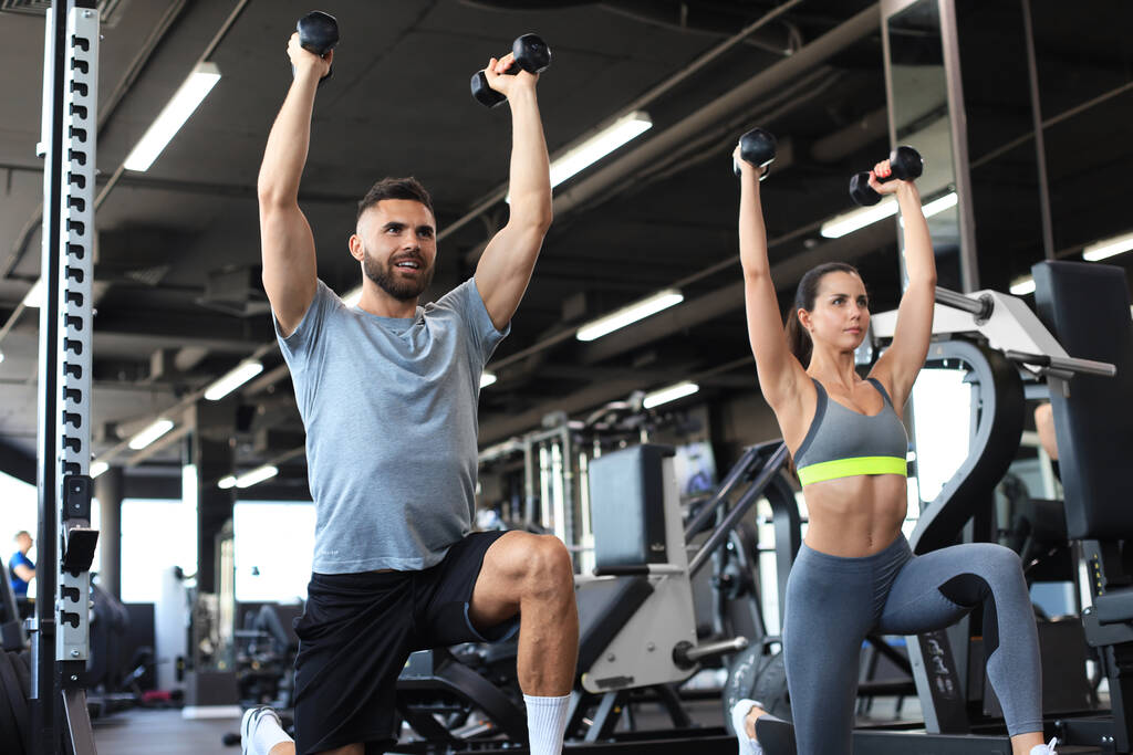 Atractivos deportistas hacen ejercicio con pesas en el gimnasio - Foto, imagen