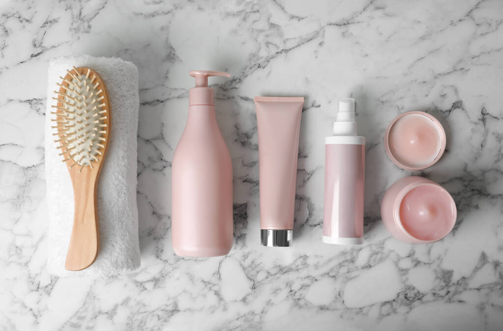 Diversi prodotti per capelli, asciugamano e spazzola su tavolo in marmo bianco, posa piatta - Foto, immagini