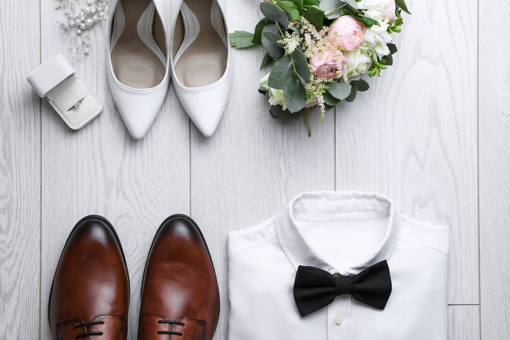 Flache Liegekomposition mit Hochzeitsschuhen für Braut und Bräutigam auf weißem Holzboden - Foto, Bild