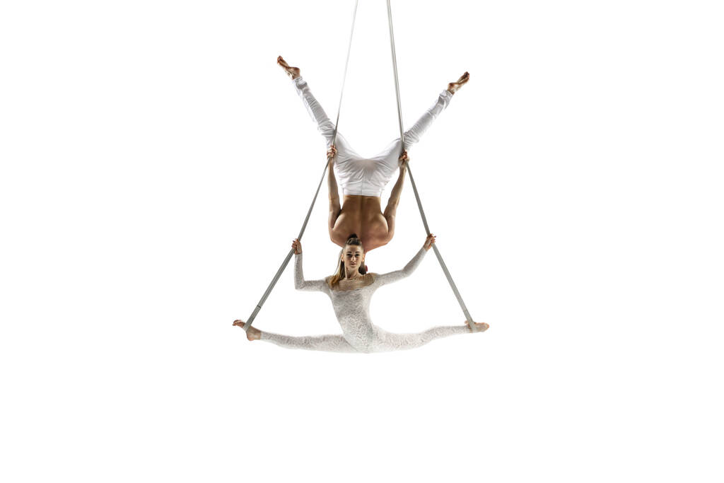 Couple of young acrobats, circus athletes isolated on white studio background. Training perfect balanced in flight - Fotoğraf, Görsel