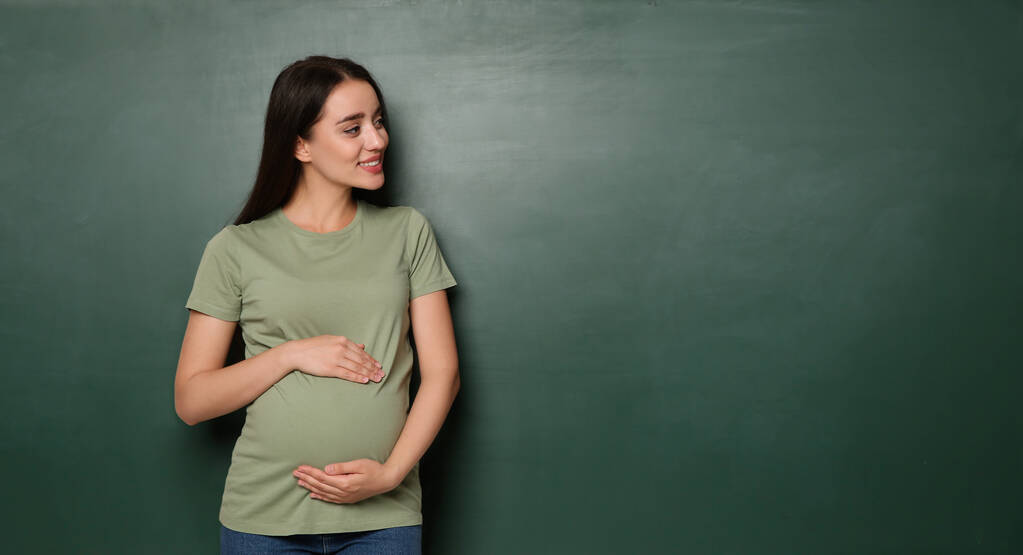 Femme enceinte près du tableau vert vide, espace pour le texte. Choisir le nom pour bébé - Photo, image