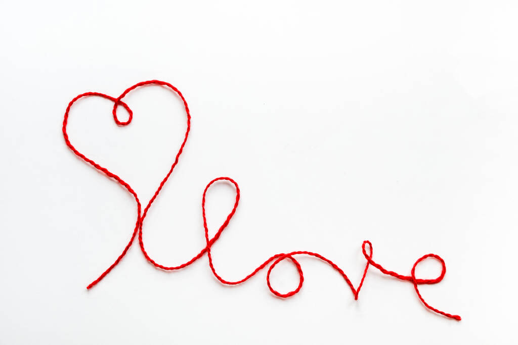 Valentýnský koncept. Červené srdce a slovo láska z vlněného lana na bílém pozadí s kopírovacím prostorem - Fotografie, Obrázek